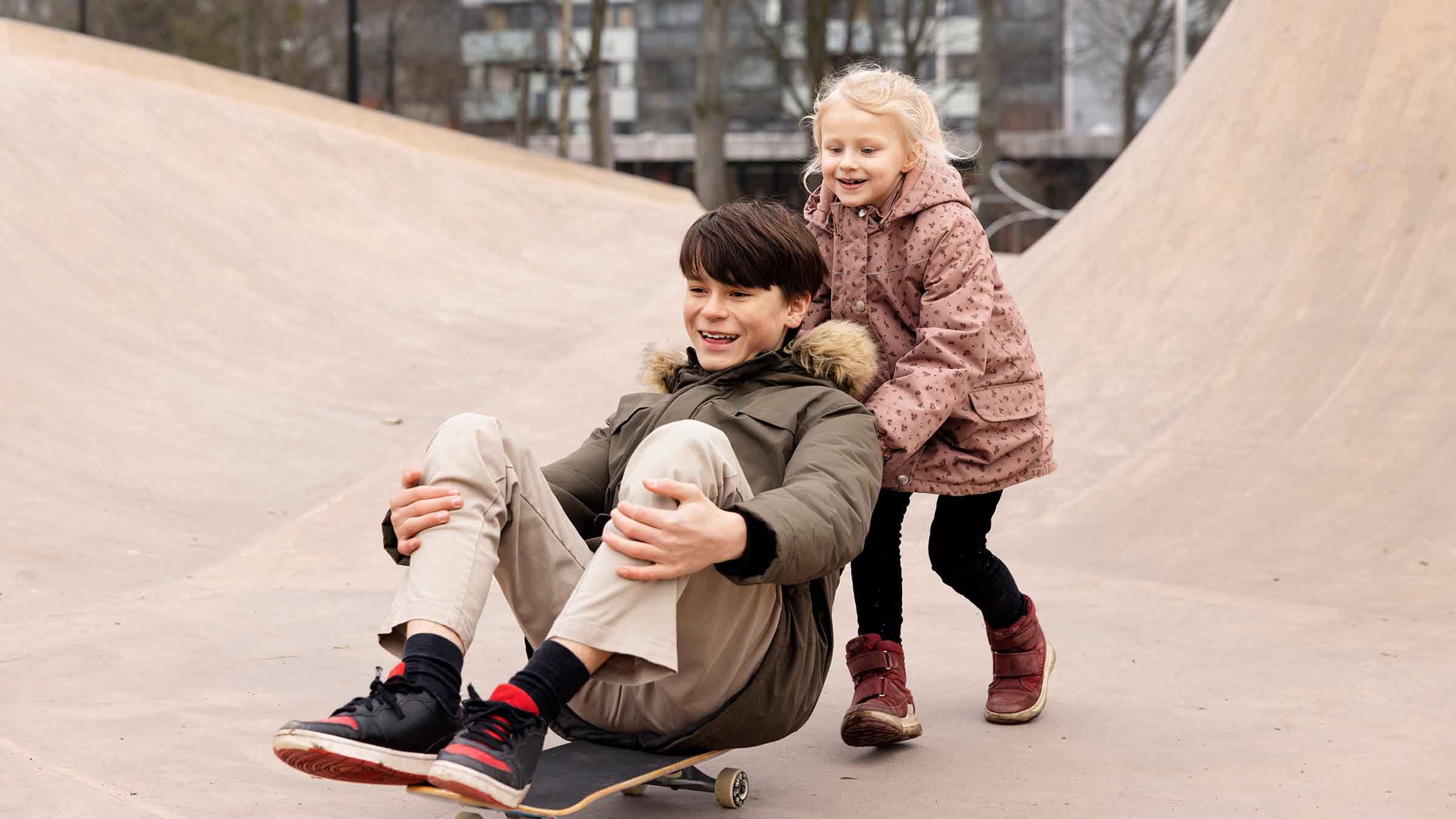 Pige skubber dreng på skateboard